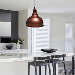 A copper-colored dome pendant light hanging over a modern kitchen island with white marble countertops and dark bar stools.